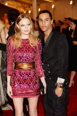 A man and woman posing at a formal event, the woman in a pink sequined dress, the man in a black suit.