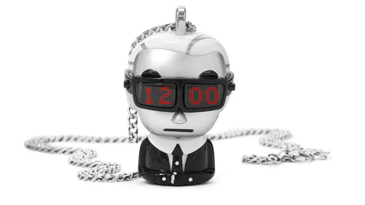 Karl Lagerfeld x Tokidoki timepiece pendant, showing a small figure in a suit with LED glasses displaying "12:00," attached to a chain.