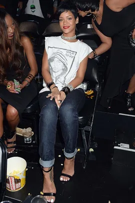 Person in a casual white graphic tee and jeans, sitting in a theater surrounded by popcorn.