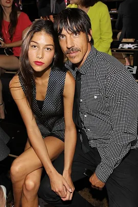 Man and woman sitting front row at New York Fashion Week, both in black and white patterned outfits.