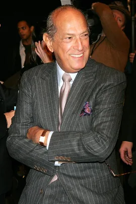 Man in a striped suit and tie, smiling with arms crossed, attends an event.