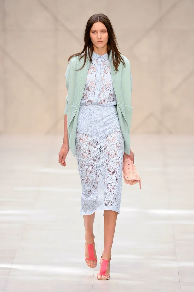 Model in Burberry SS14 outfit: mint cardigan, lace dress, pink clutch and heels, walking on runway.