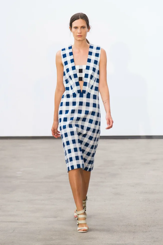 Model in blue and white checkered dress walking on a minimalist runway, showcasing Derek Lam Spring/Summer 2014 collection.