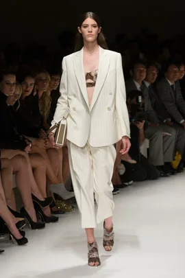 Model walks runway in white pinstripe suit, snake print top, and heels at Salvatore Ferragamo SS14 fashion show.