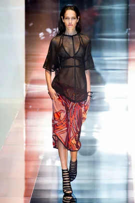 Model walks the runway wearing a black mesh top and red patterned skirt during Gucci Spring/Summer 2014 fashion show.