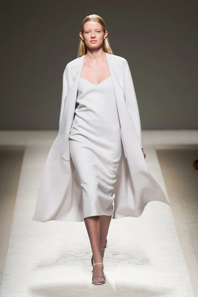 Model in a white slip dress with matching coat on the Max Mara SS14 runway.