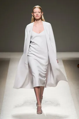 Model in a white slip dress with matching coat on the Max Mara SS14 runway.