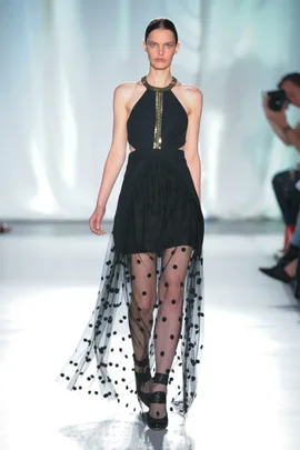 Model on runway wearing black dress with polka dot tulle and metallic neckline, from Sass and Bide SS14 collection.