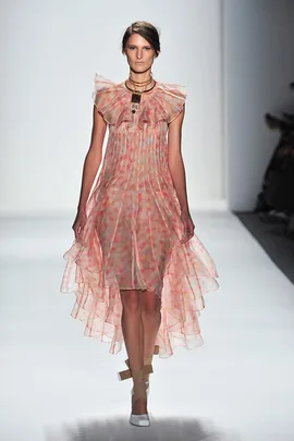 Model in sheer, peach-toned, layered dress on runway, wearing statement choker necklace, Zimmermann SS14 fashion show.