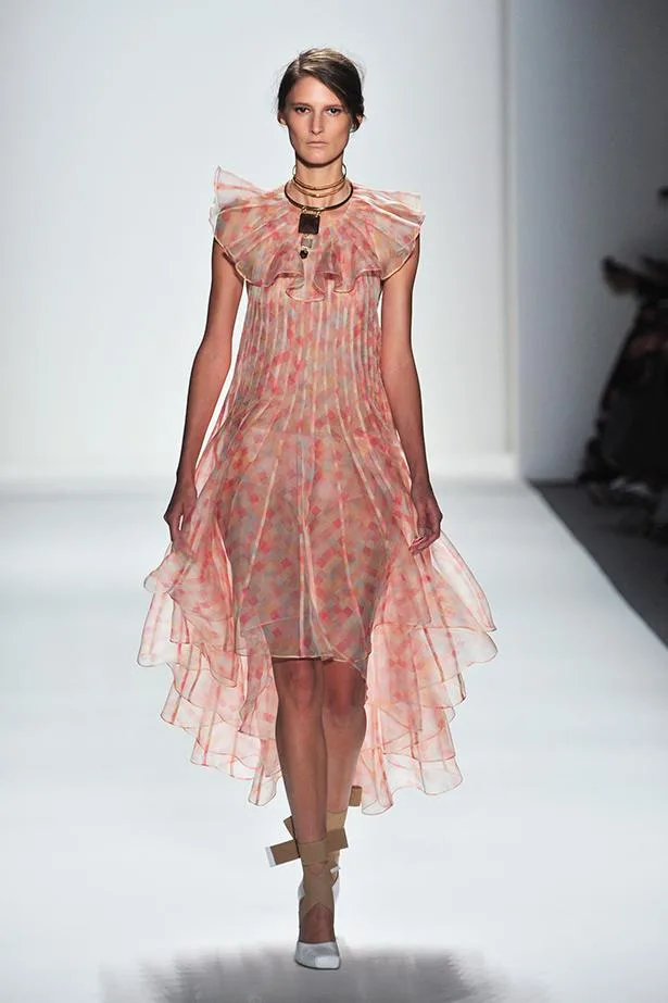 Model in sheer, peach-toned, layered dress on runway, wearing statement choker necklace, Zimmermann SS14 fashion show.