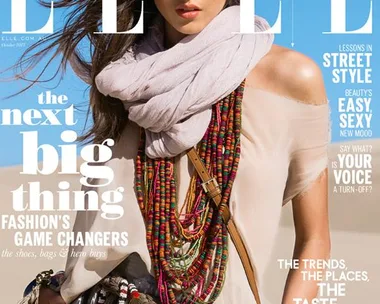 Cover of Elle magazine featuring a woman in a beige top, colorful scarf, and layered necklaces against a blue sky background.