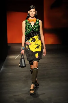 Model on runway in Prada Spring/Summer 2014 dress with vibrant face print and embellishments.