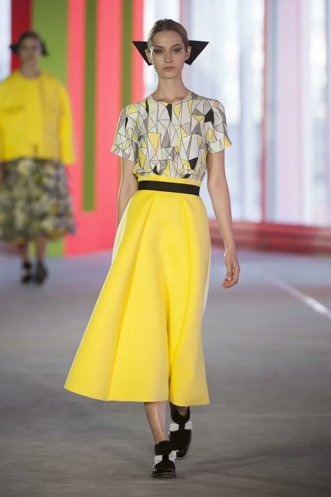 Model on runway wears geometric yellow top and skirt by Roksanda Ilincic, Spring/Summer 2014 collection.