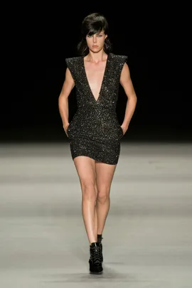 Model in a black, glittering deep V-neck dress, walking on the runway at Saint Laurent SS14 show.