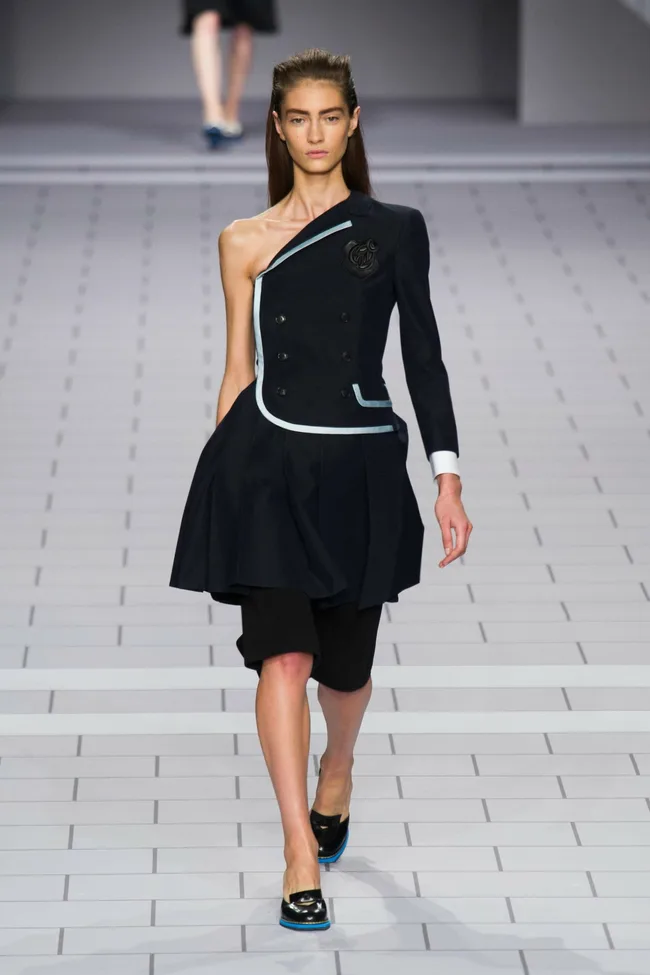 Model walks runway in asymmetrical black dress with light blue trim, featuring one sleeve, for Viktor & Rolf SS14 collection.