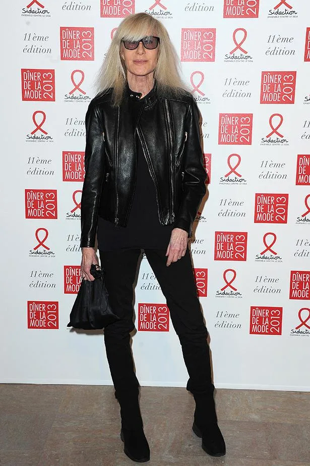 Person in black leather outfit at Dîner de la Mode 2013 event, posing in front of event backdrop.