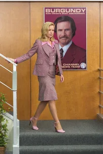 Veronica Corningstone walks down stairs in front of Ron Burgundy poster from "Anchorman: The Legend of Ron Burgundy."