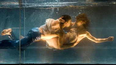 Two performers underwater in an intimate embrace, part of a dance performance at the Sydney Festival.