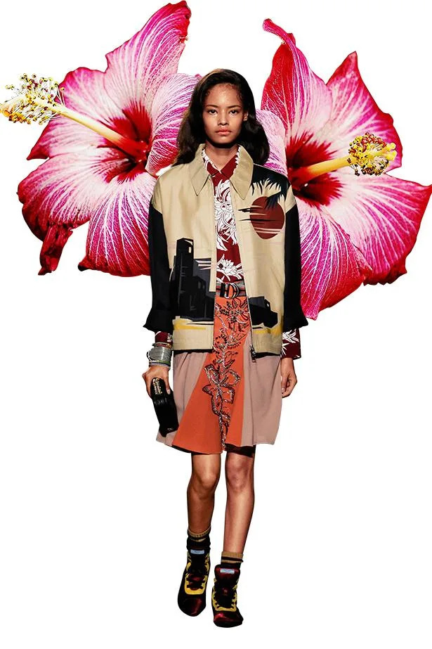 Model in colorful urban print outfit set against a backdrop of two large pink hibiscus flowers.