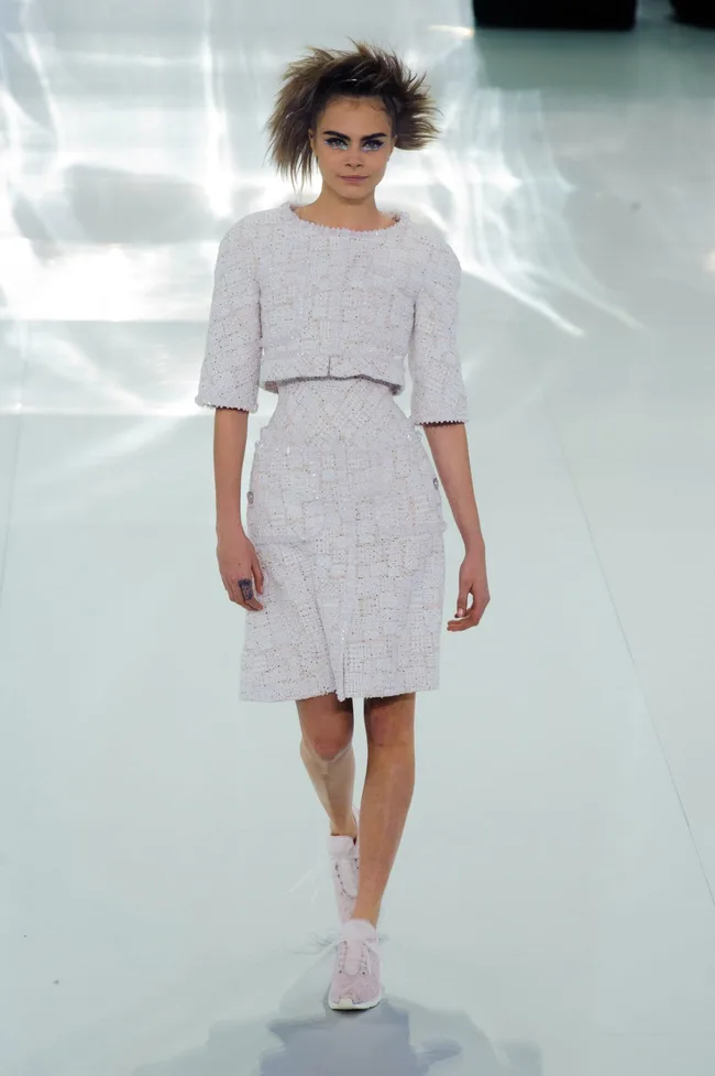 Model walks in Chanel tweed outfit and pink sneakers, showcasing the Haute Couture Spring/Summer 2014 collection.