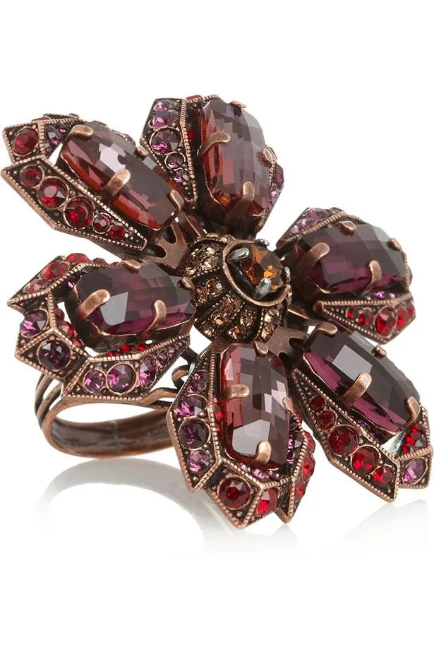 Antique-style ring with large purple and red gemstones, arranged in a floral pattern, set in ornate metal detailing.