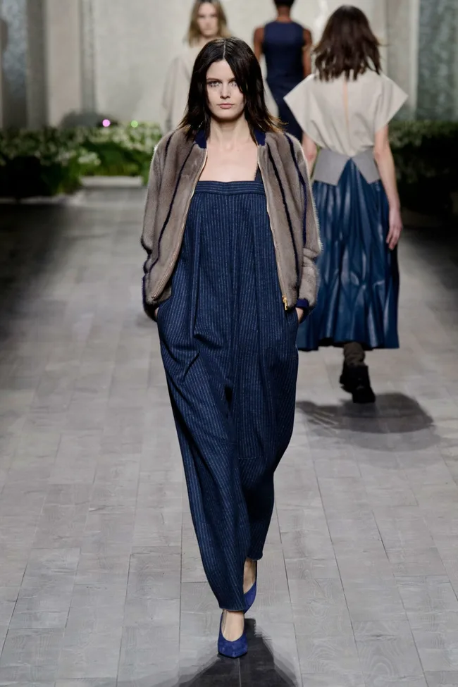 Model on runway in Vionnet Fall/Winter 2014 collection; wearing a fur jacket, blue dress, and heels.