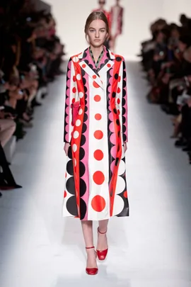 Model walks runway in Valentino Fall/Winter 2014-15 polka dot coat and red heels at fashion show.