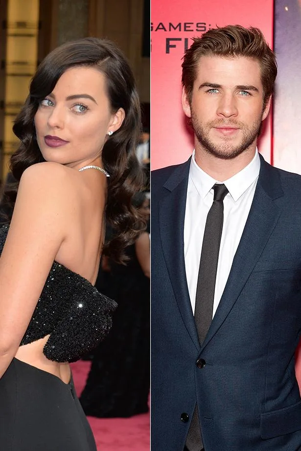 Celebrities posing on the red carpet, woman in black gown and man in a blue suit with a black tie.