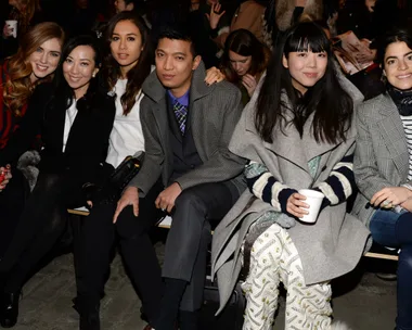 Group of six fashionable individuals sitting together at a fashion event.