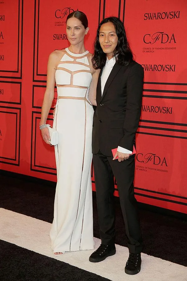 Two fashionably dressed individuals pose together on a red carpet at a CFDA event.