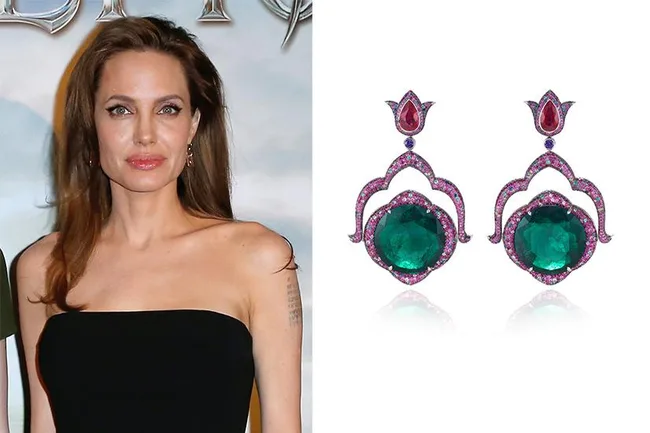 Elegant woman in black strapless dress next to emerald and ruby earrings on white background.
