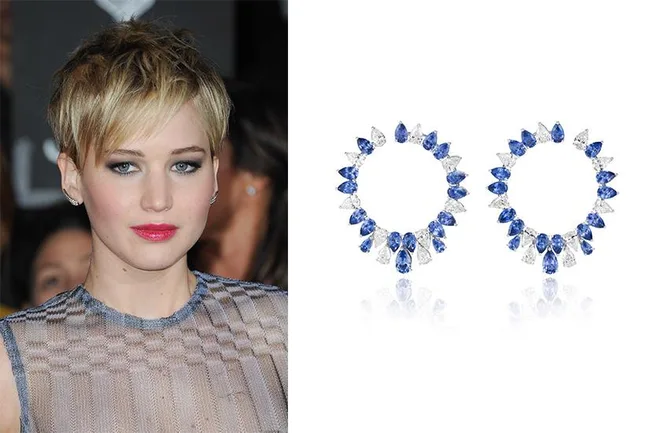 Blonde woman with short hair wearing a sheer dress, next to blue and white gemstone hoop earrings.