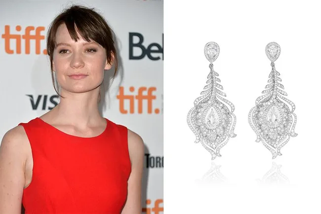 A person in a red dress at a TIFF event beside a pair of ornate silver earrings.