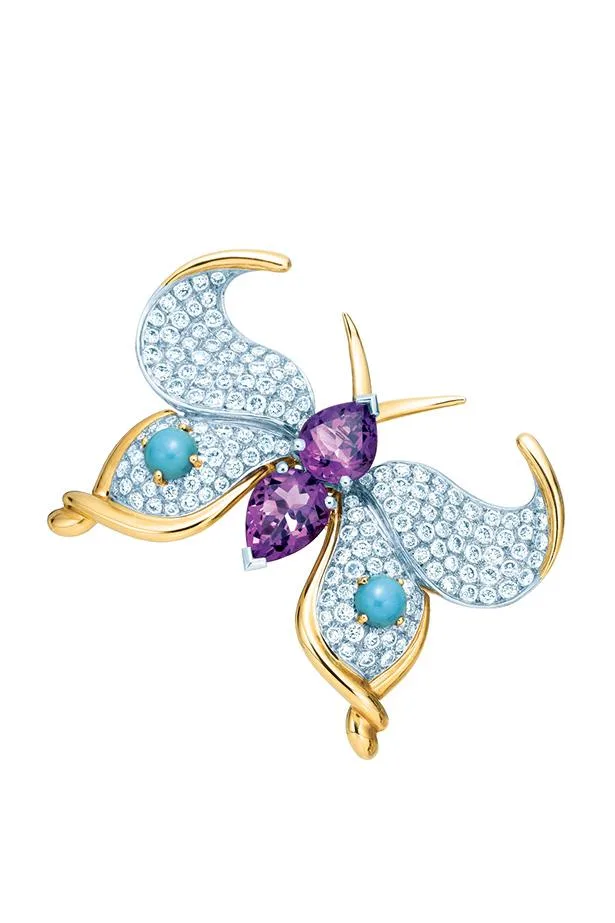 A butterfly brooch with diamonds, purple gemstones, turquoise accents, and gold details.