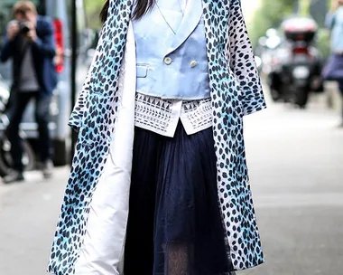 Woman wearing a blue animal print coat, light blue blazer, and tulle skirt on a city street.