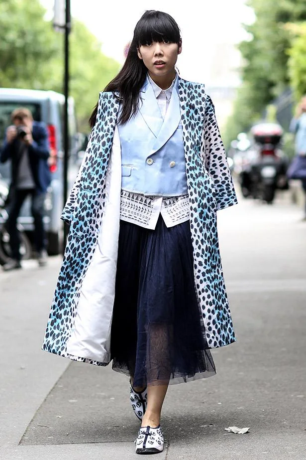 Woman wearing a blue animal print coat, light blue blazer, and tulle skirt on a city street.