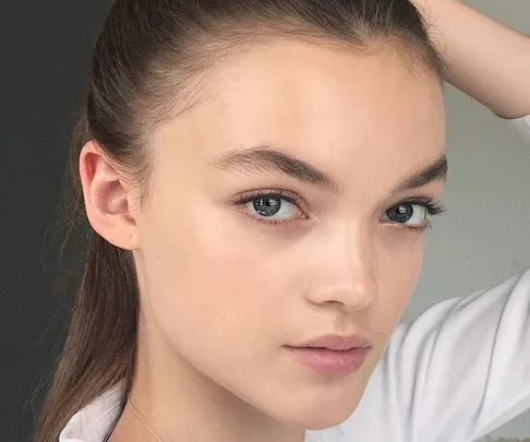 Close-up of a young woman with clear skin, holding her hair back, showcasing a fresh and clean face.