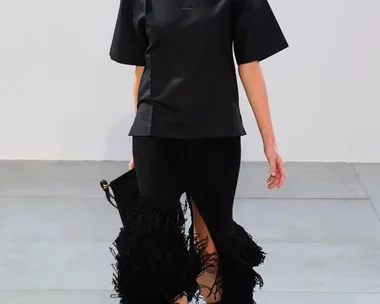 Model walking runway in black V-neck top and fringed skirt, part of Celine Spring/Summer 2015 collection.