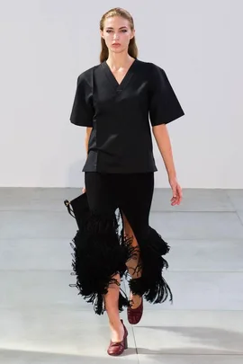 Model walking runway in black V-neck top and fringed skirt, part of Celine Spring/Summer 2015 collection.