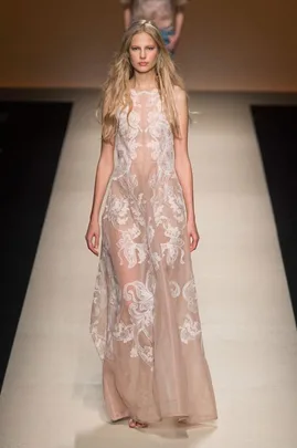 Model in a sheer, embroidered, floor-length dress on the runway, showcasing a bridal fashion alternative.