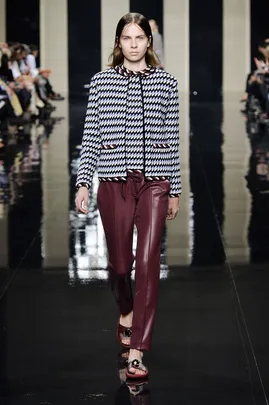 Model walks the runway in a houndstooth jacket and burgundy leather pants at Christopher Kane SS15 fashion show.