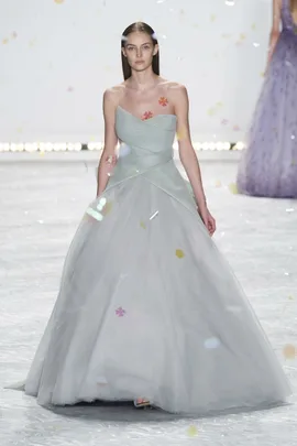 Model in a strapless, light grey gown with tulle skirt walking runway, floral appliqués on bodice, Monique Lhuillier SS15.