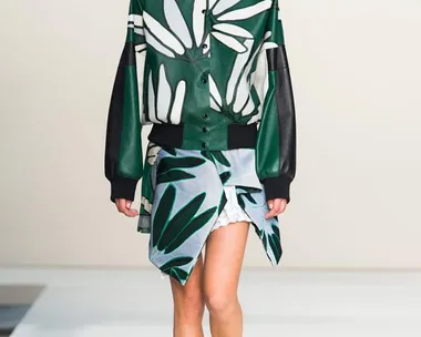 Model walks runway in Marni SS15 collection wearing green and white leaf-patterned jacket and matching skirt.