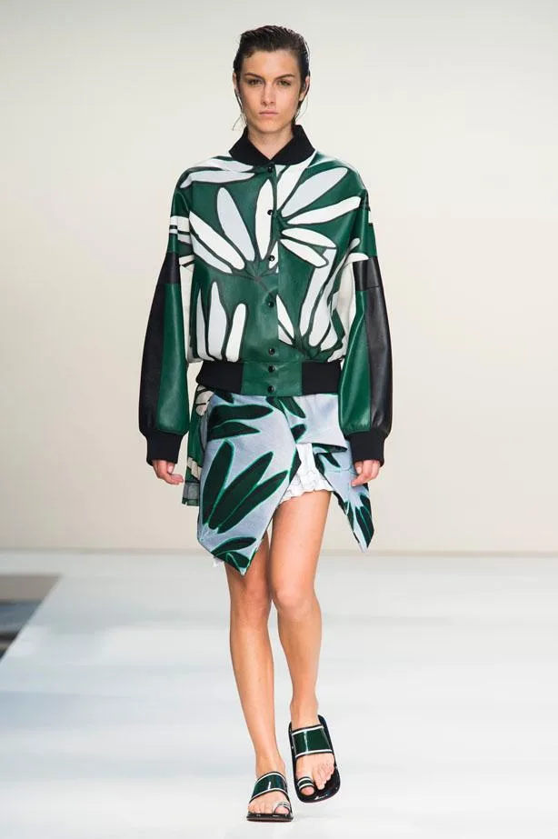 Model walks runway in Marni SS15 collection wearing green and white leaf-patterned jacket and matching skirt.