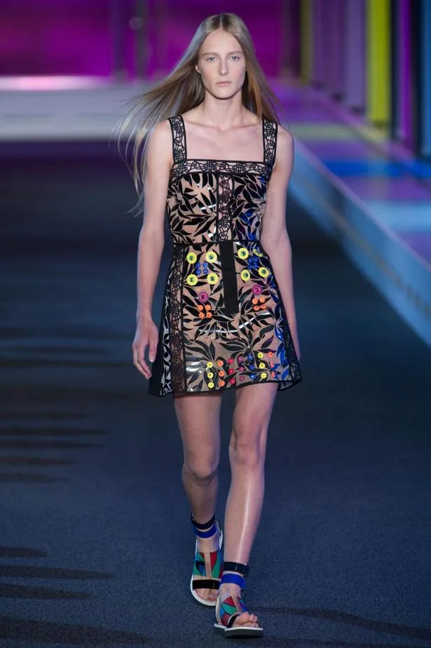 Model walking runway in a colorful, floral dress with geometric sandals during Peter Pilotto SS15 fashion show.