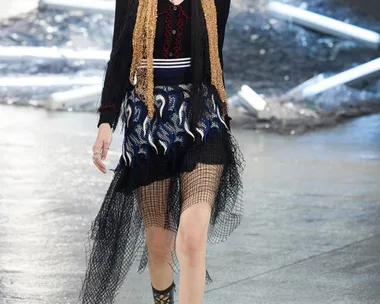 Model on runway wearing eclectic Rodarte SS15 outfit with fringe details, mesh, sunglasses, and lace-up sandals.