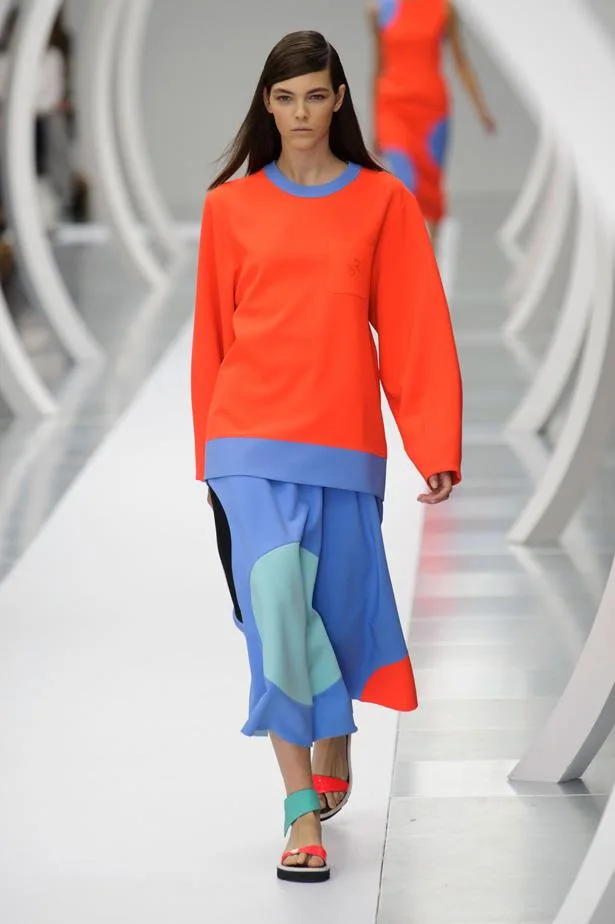 Model in orange top and blue skirt walks runway at Roksanda Ilincic SS15 fashion show.