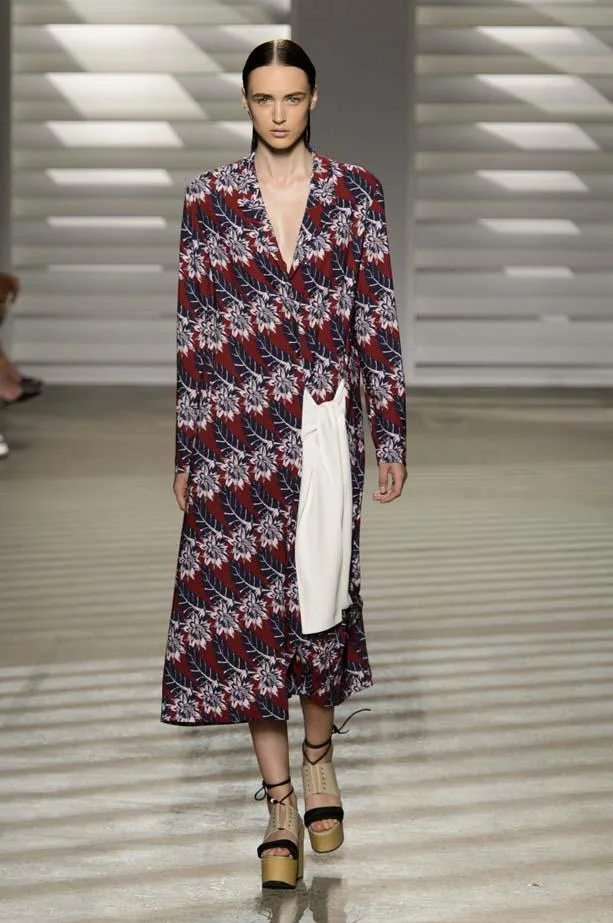 Model in floral long coat with a plunging neckline walks the runway, wearing platform sandals at Thakoon SS15.