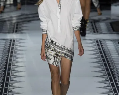 Model walking the runway in Versace Spring/Summer 2015 collection, wearing a white shirt and patterned skirt.