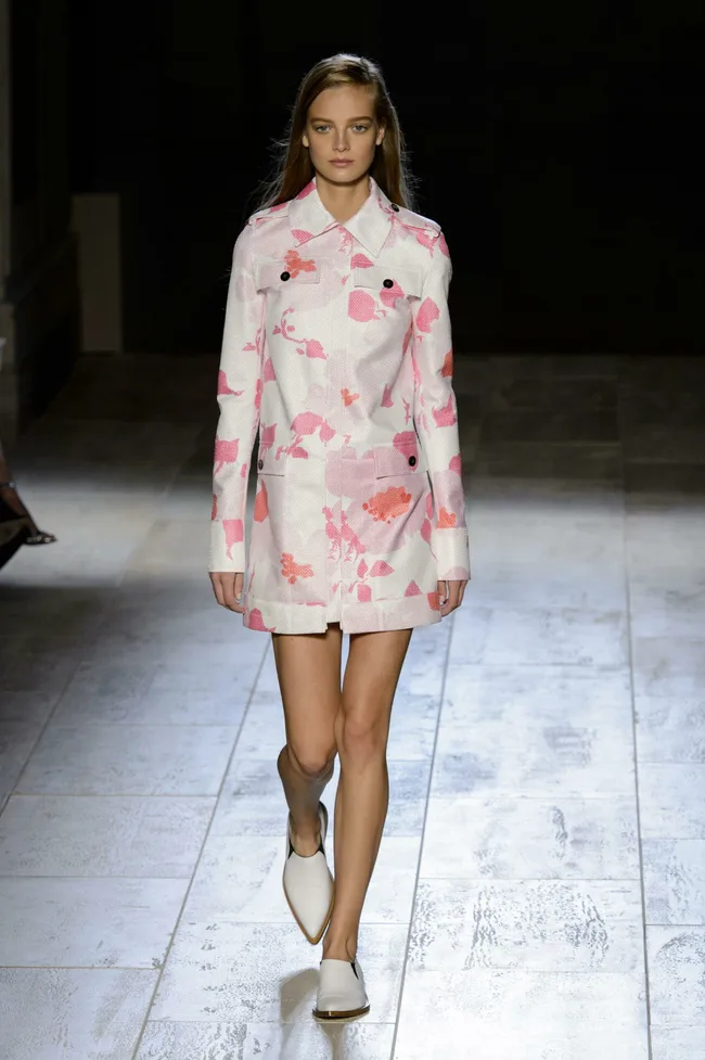 Model in pink floral coat and white shoes walking runway at Victoria Beckham SS15 show.